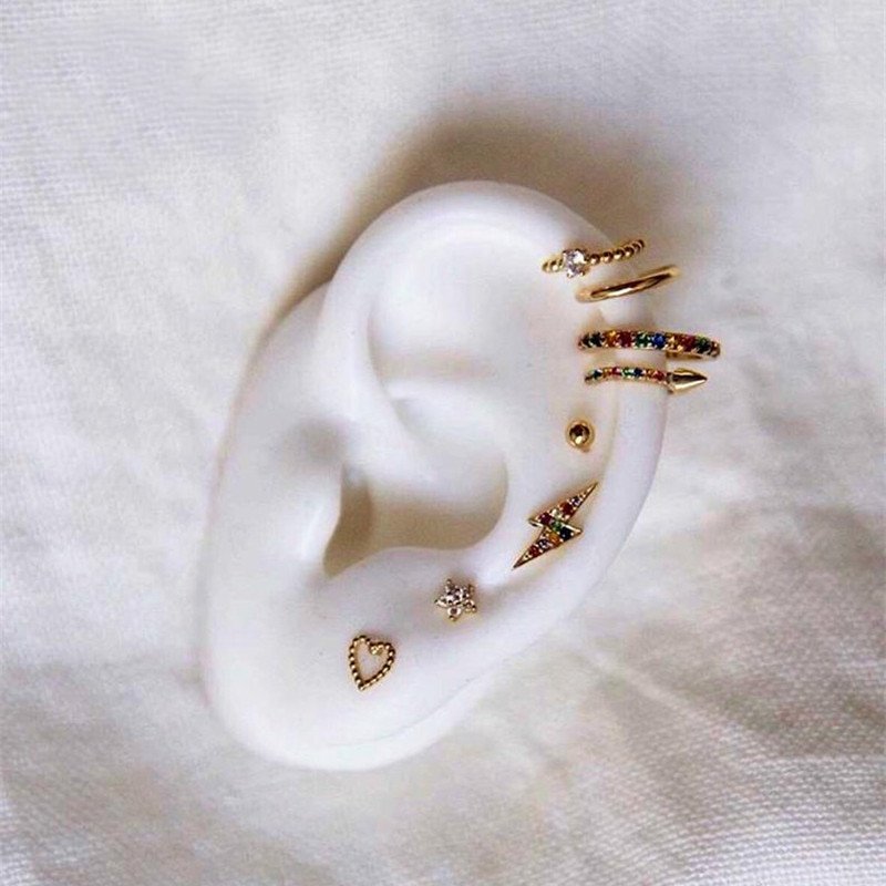 Multiple gold earrings displayed on a faux ear.
