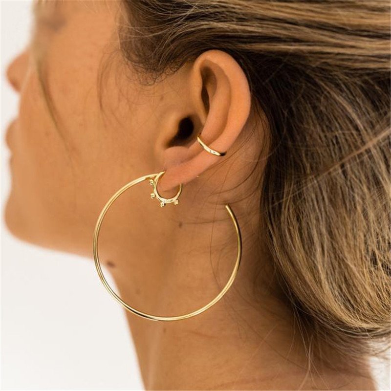 a woman wearing a large hoop earring and ear cuff.