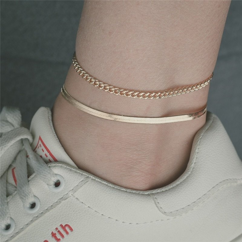 A woman wearing two gold anklets.