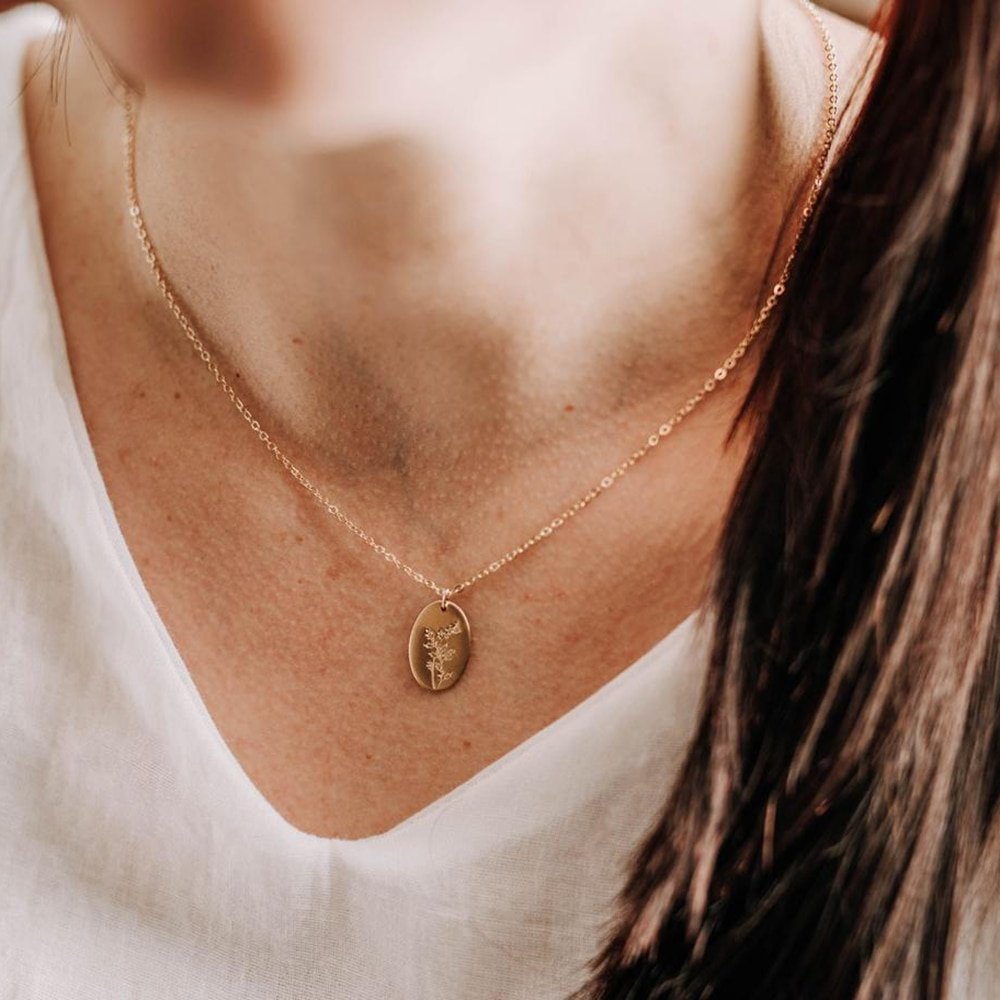 A woman wearing a gold birth flower necklace.