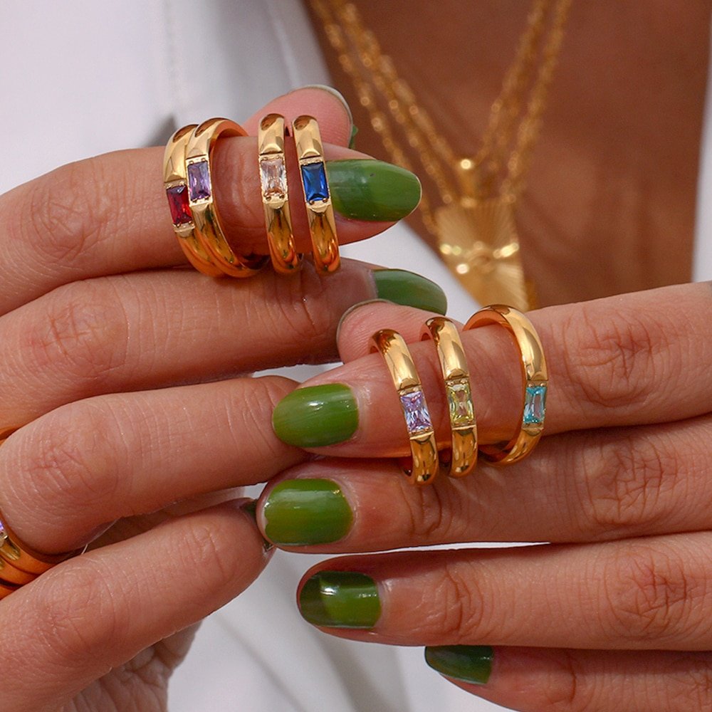 Woman holding a bunch of gold birthstone rings.
