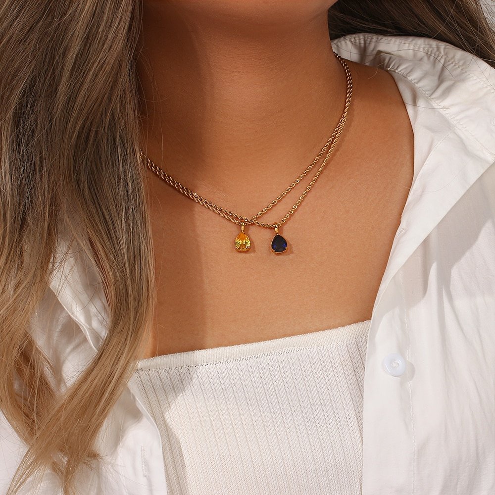 A model wearing two Birthstone CZ Teardrop Gold Necklaces.