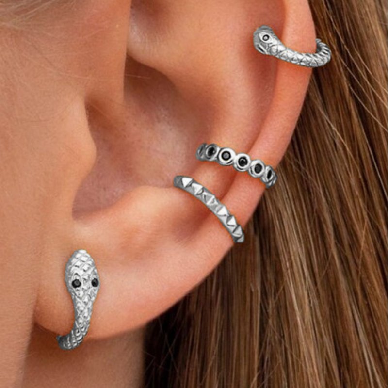 A model wearing multiple silver earrings with black stones.