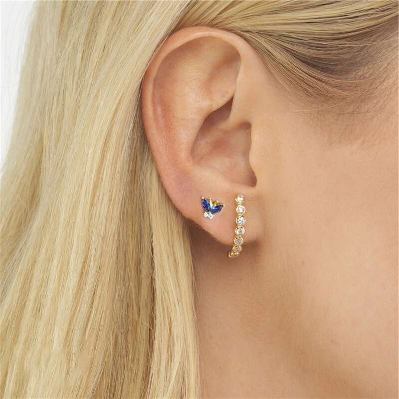 A woman wearing the Blue CZ Butterfly Studs.