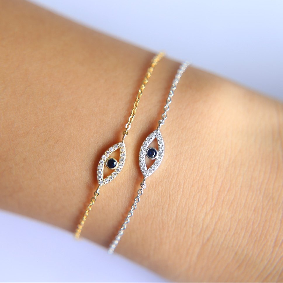 A model wearing a gold and silver evil eye bracelet.