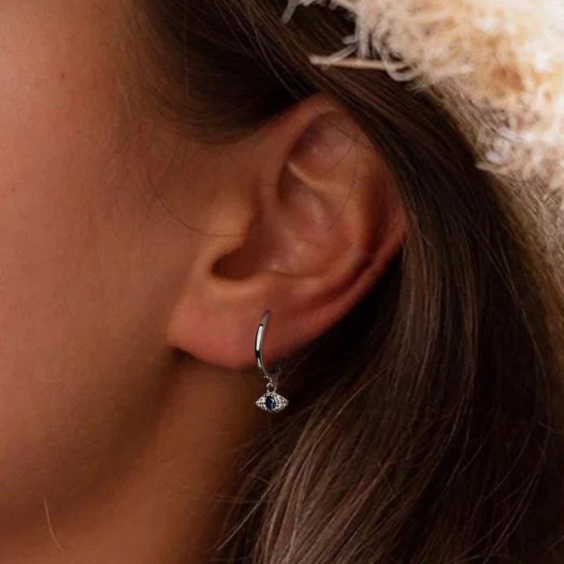 A woman modeling the silver evil eye CZ earrings.