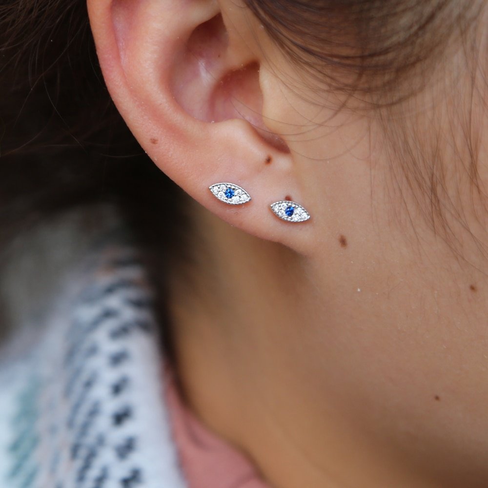 A model wearing two Blue CZ Evil Eye Studs in silver in one ear.