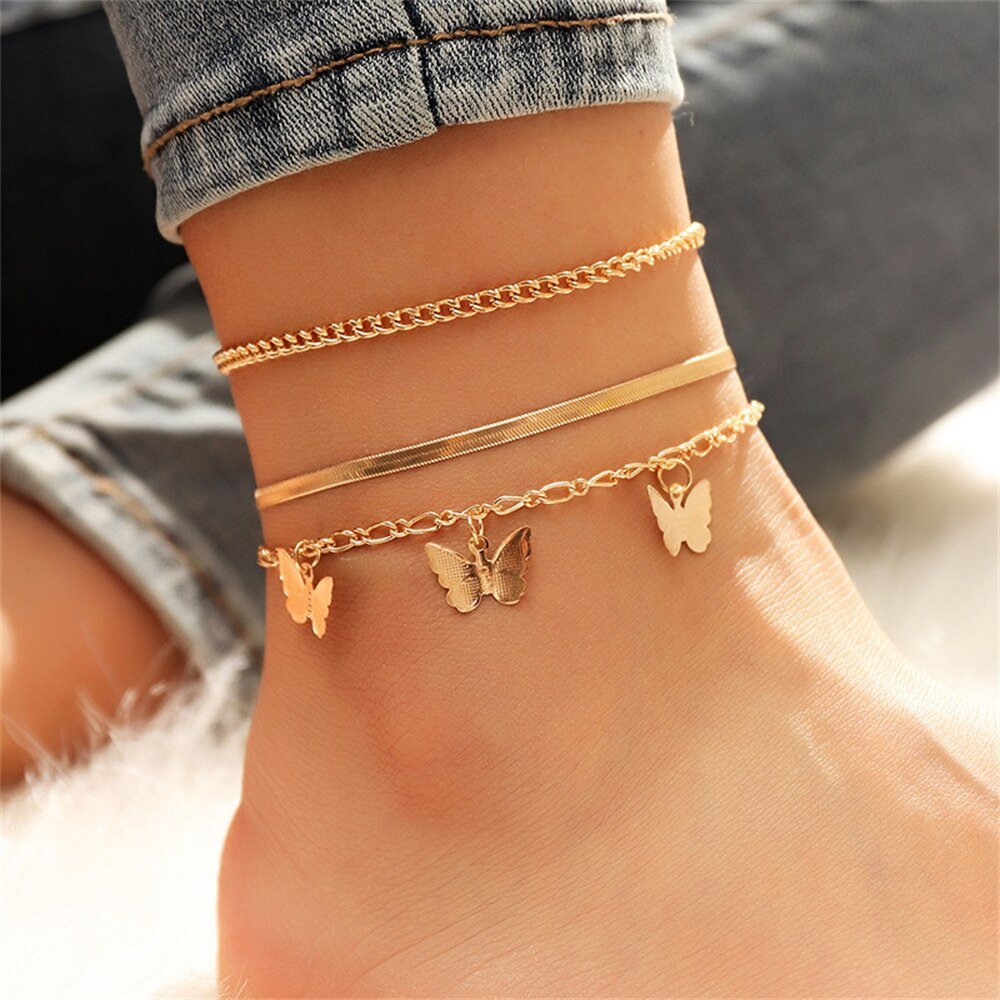 A woman wearing multiple gold butterfly anklets.
