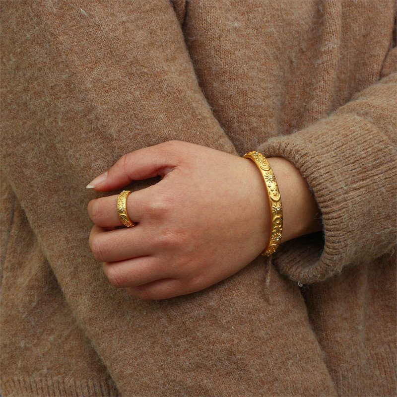 A woman wearing a think gold ring and bangle.