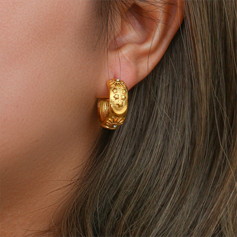 A model wearing thick gold hoop earrings.