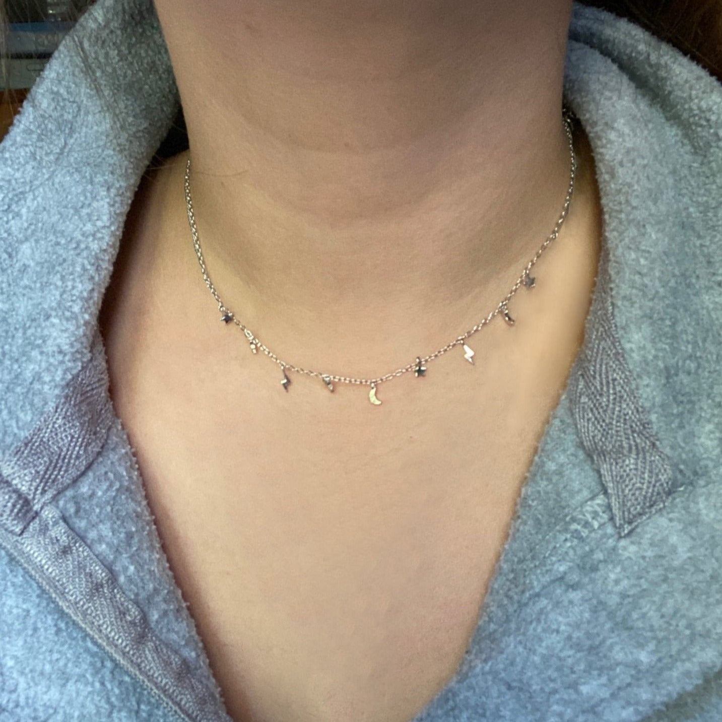 A woman wearing a delicate celestial necklace.