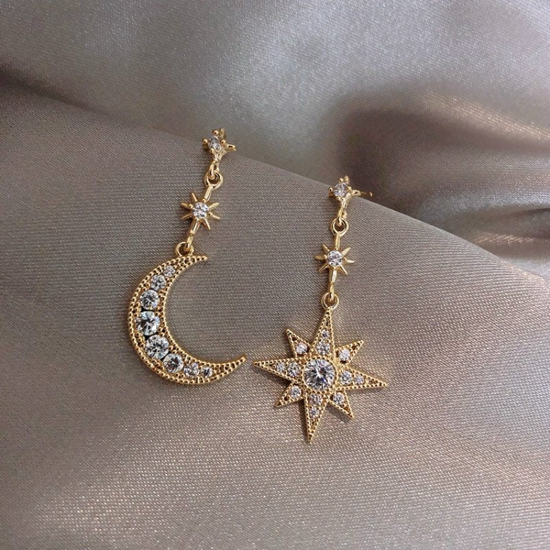 Gold CZ encrusted star and moon drop earrings.