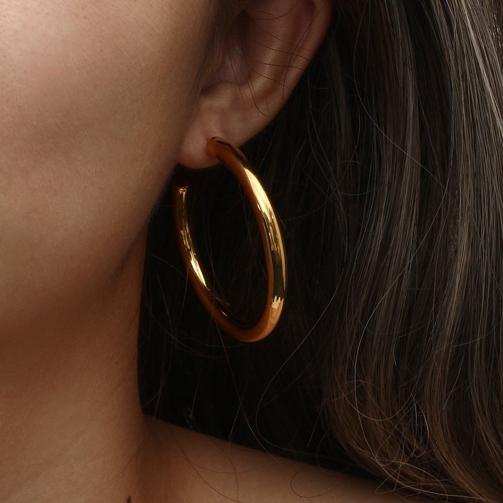 A woman wearing thick gold hoop earrings.