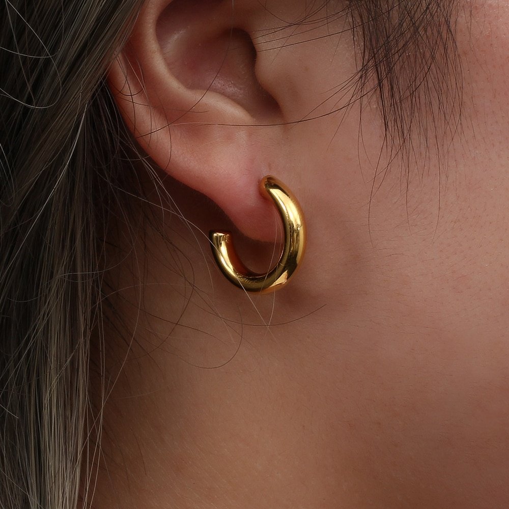 A woman wearing think small hoop earrings.