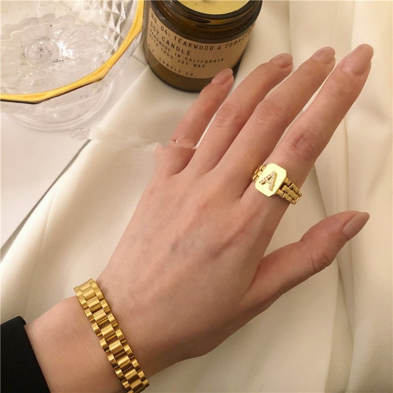A model wearing a chunky gold initial ring with the letter A.