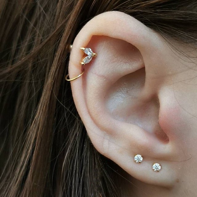 A woman wearing multiple gold earrings.