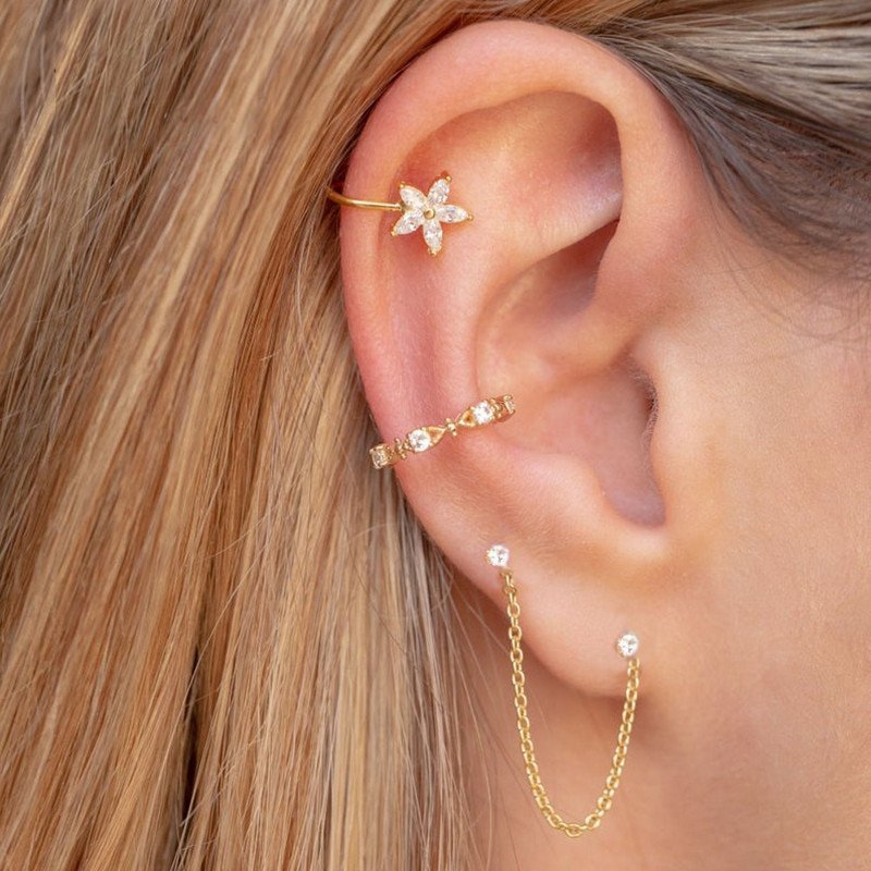 A model wearing multiple gold studs and ear cuffs.