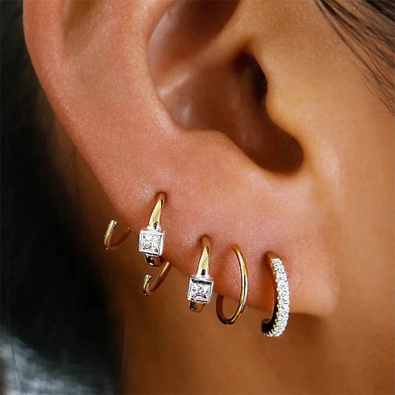 A model wearing multiple gold mini hoop earrings.