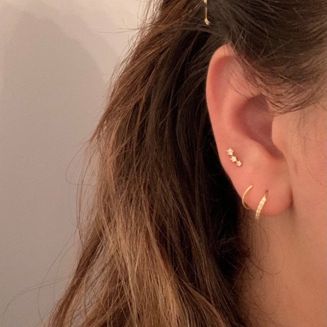 A woman wearing mini gold CZ hoops.