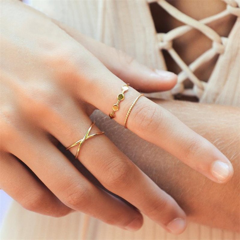 A woman wearing three dainty gold rings.
