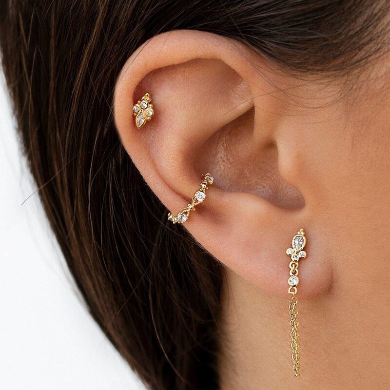A model wearing three gold earrings with CZ stones.
