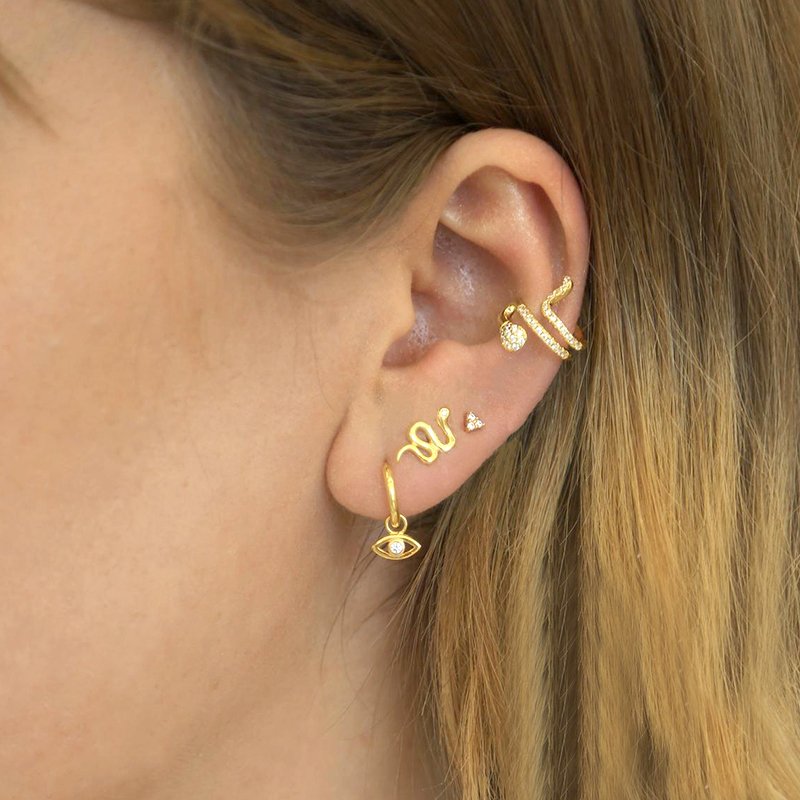 A model wearing multiple snake earrings.