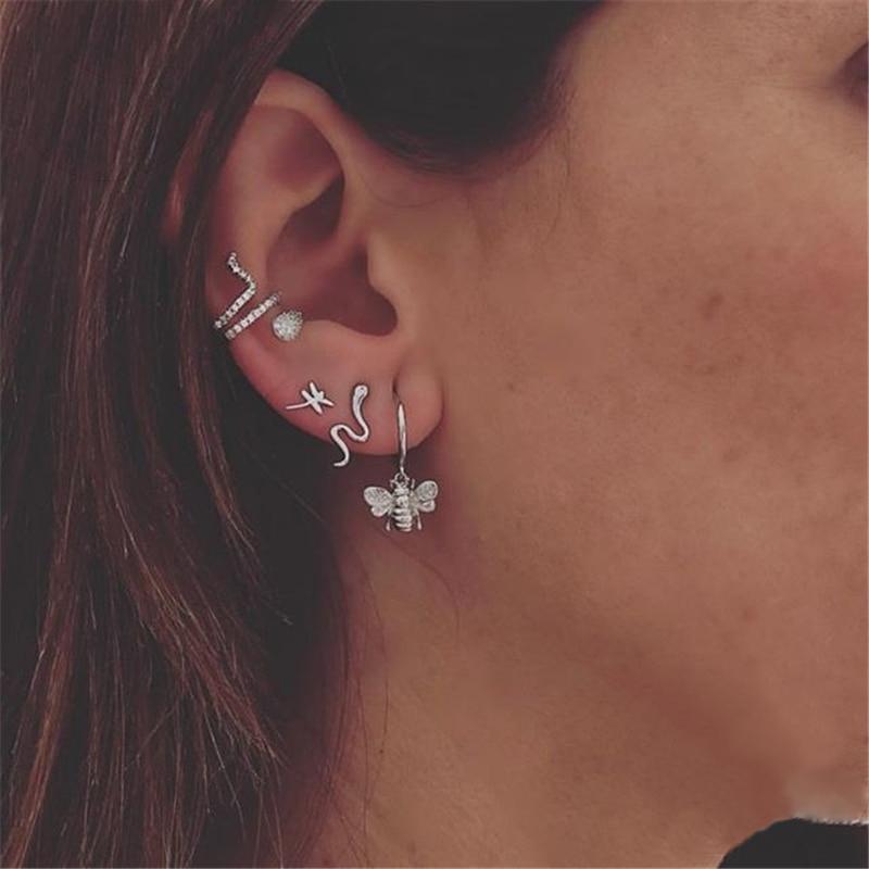 A model wearing multiple silver serpent earrings.