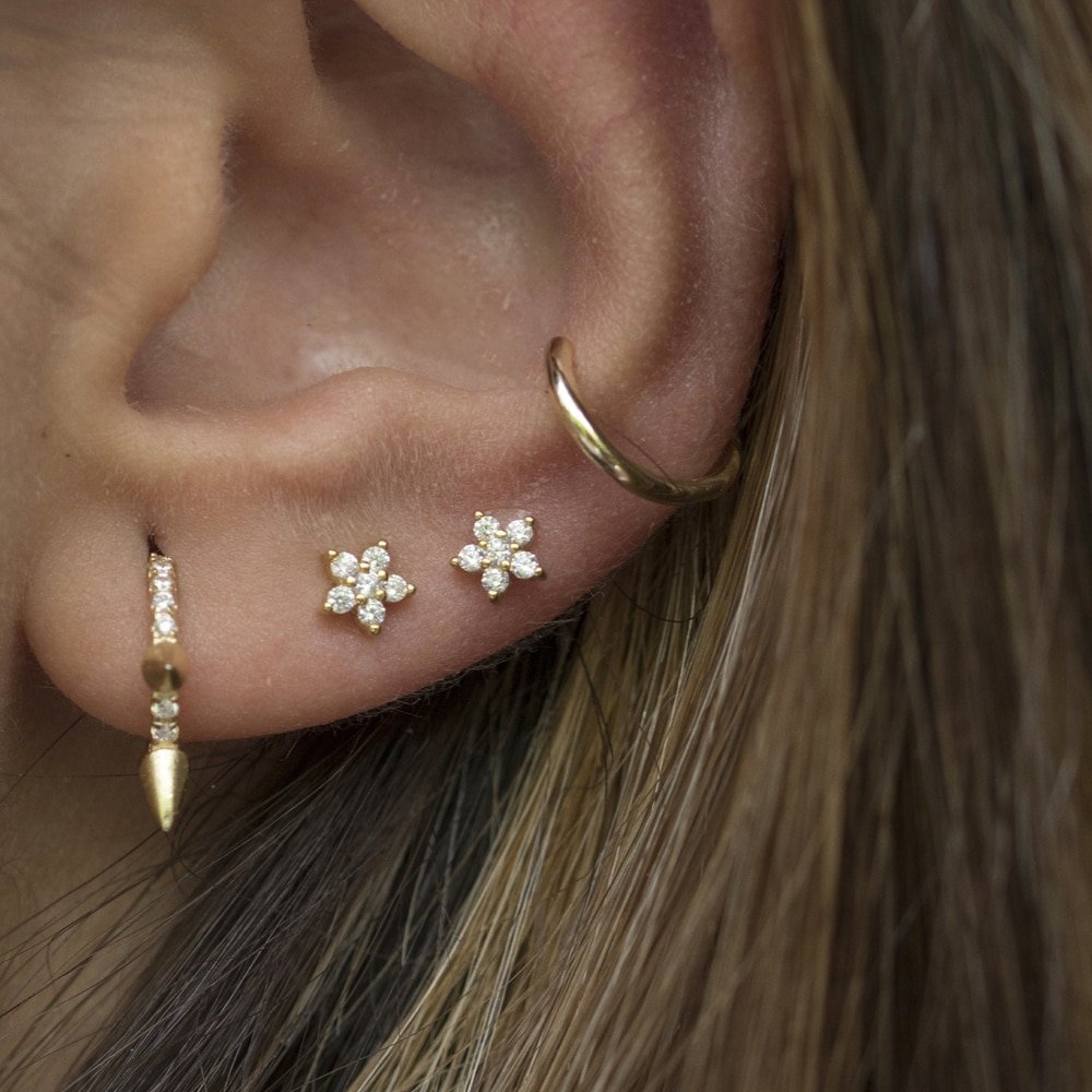 A woman wearing CZ flower stud earrings.