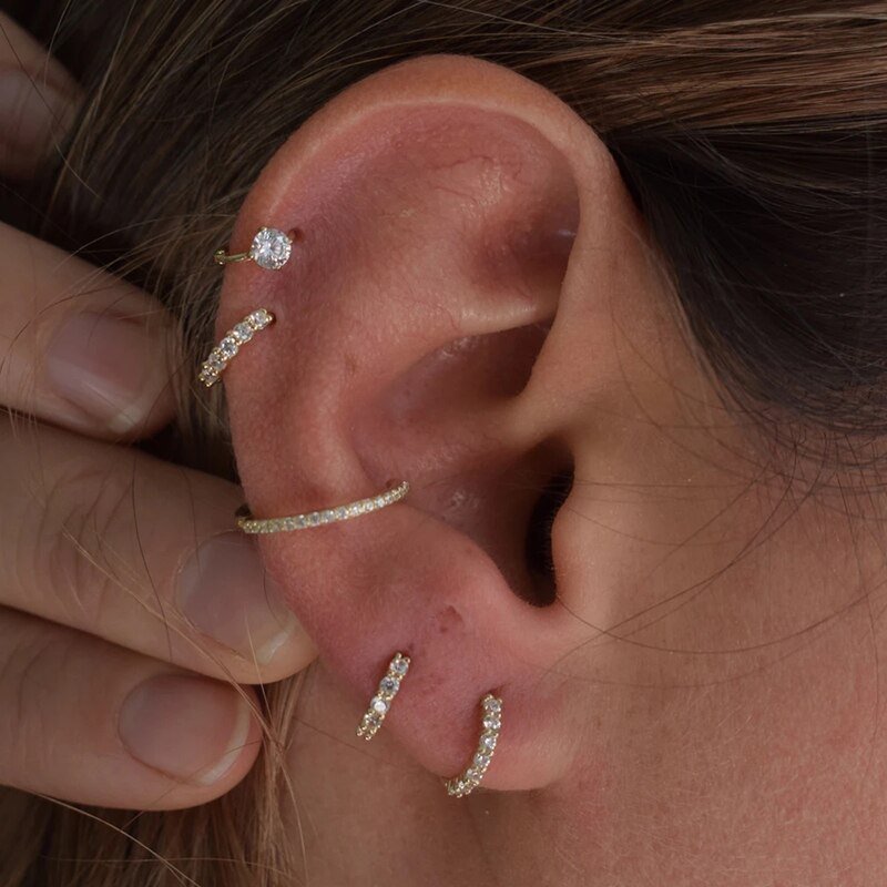 A model wearing multiple gold CZ cartilage hoop earrings.