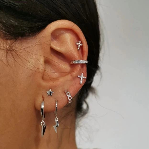 A model wearing multiple silver stud earrings.