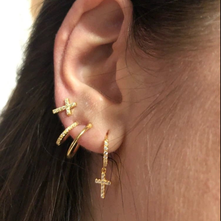 A model wearing gold CZ pave cross hoops and stud earrings.