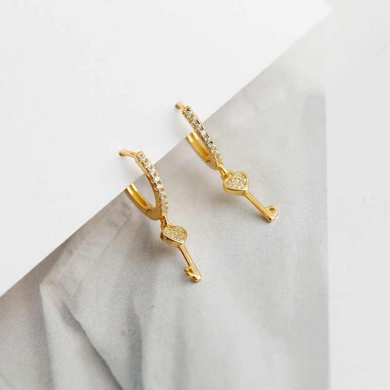 Closeupp of the gold heart key earrings.