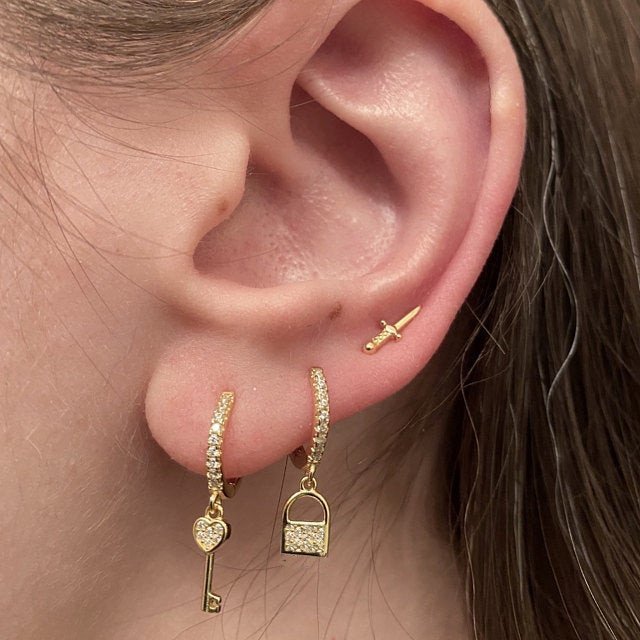 A model wearing padlock and key earrings.