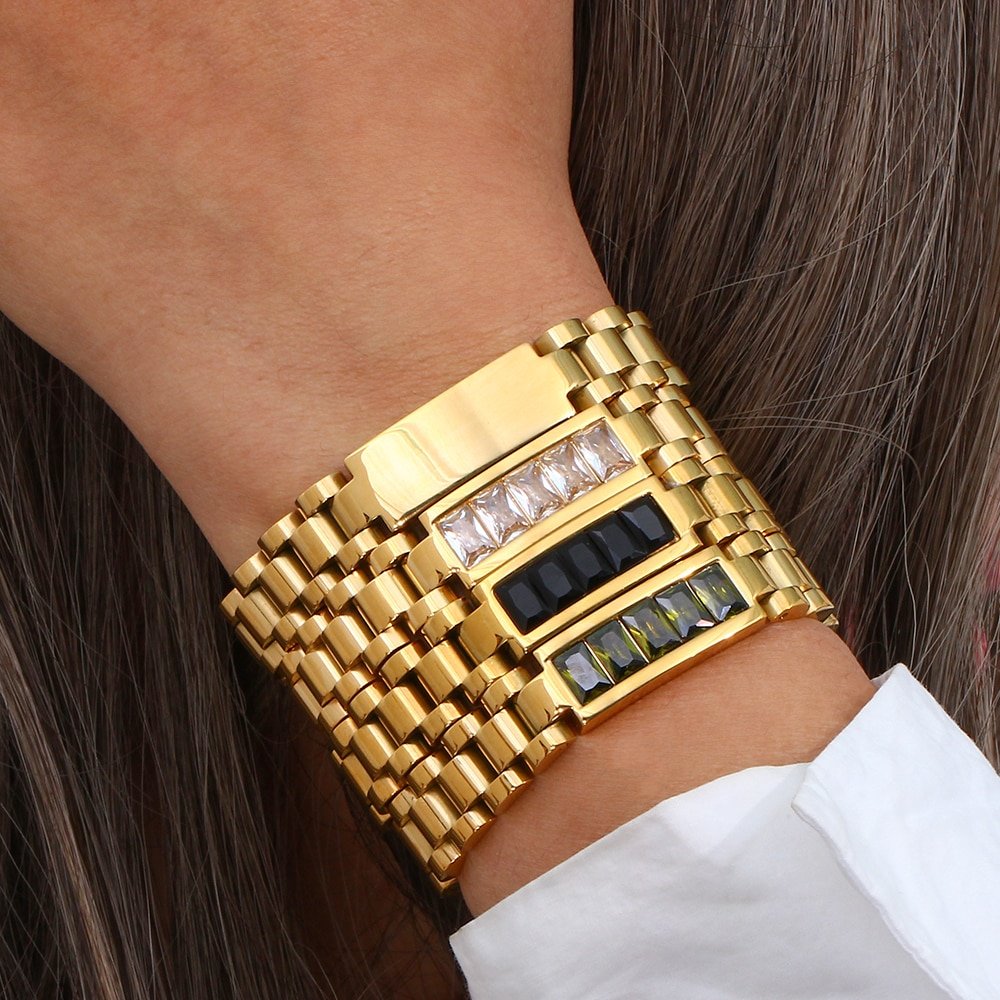 A model wearing multiple chunky gold bracelets.