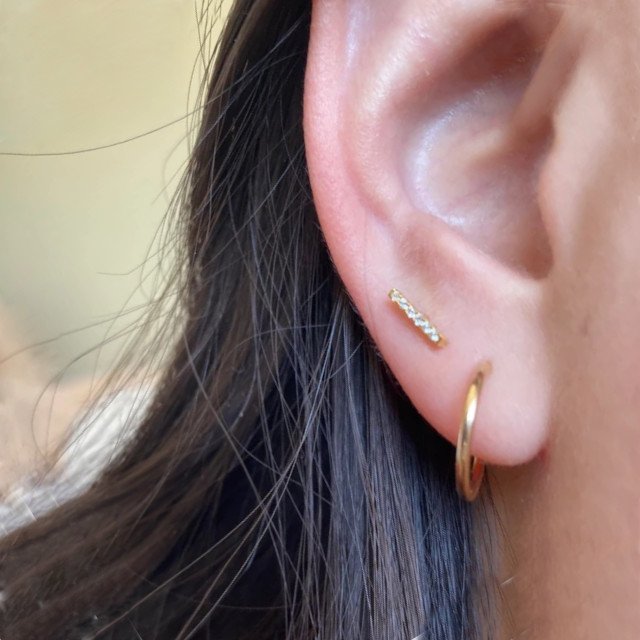A woman wearing dainty gold earrings.