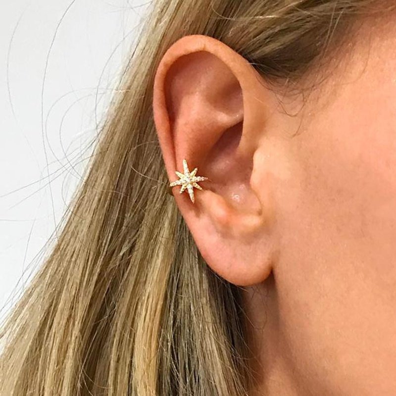 A woman wearing a gold star ear cuff with sparkling CZ stones.