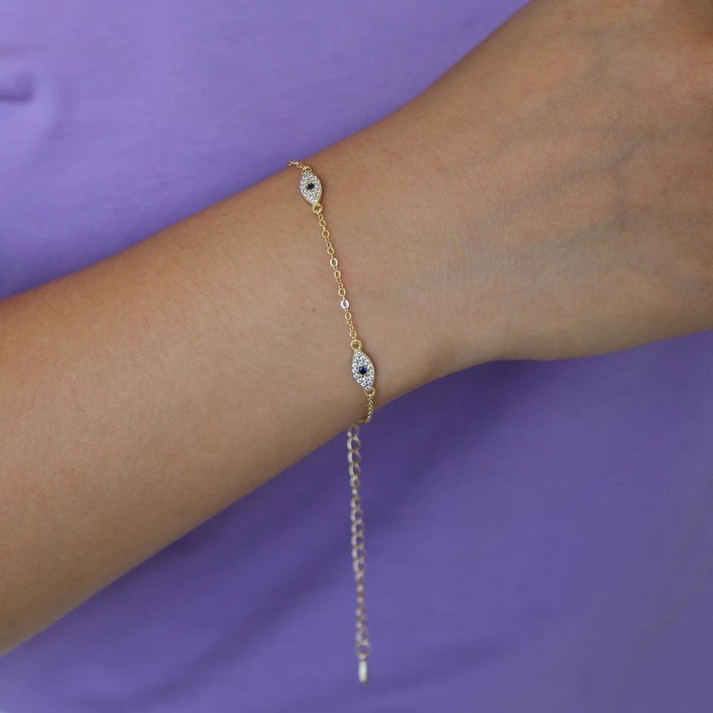 A model wearing a gold evil eye chain bracelet.