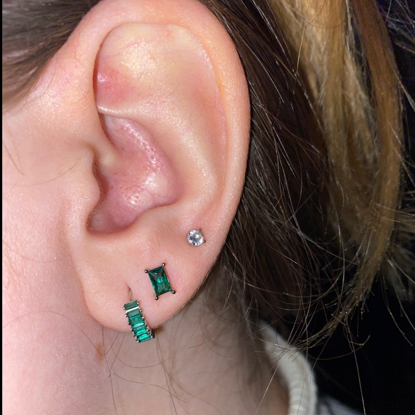 A model wearing green gemstone earrings.