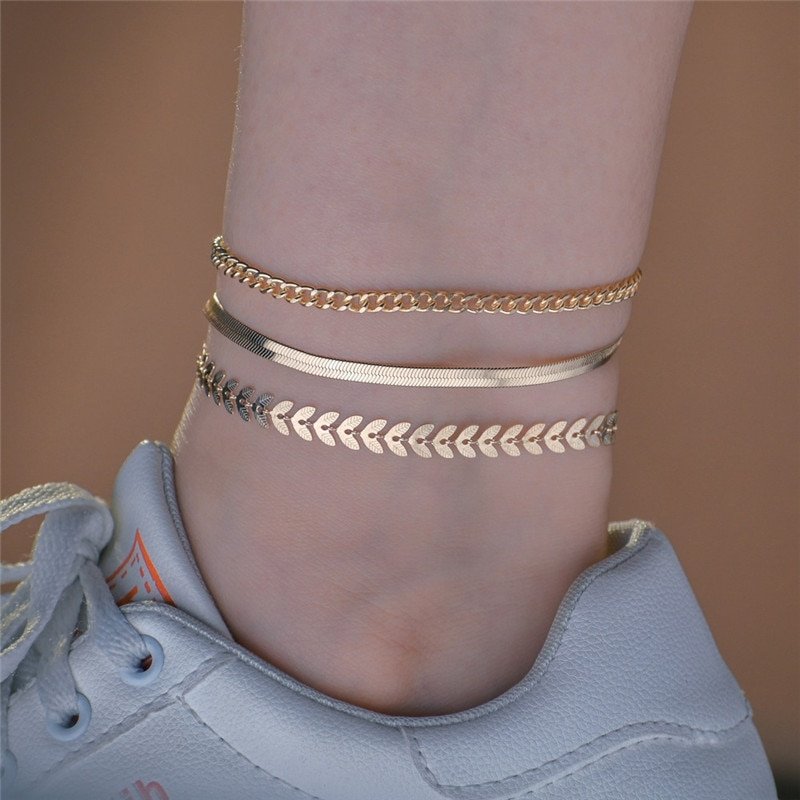 A woman wearing three gold anklet chains.