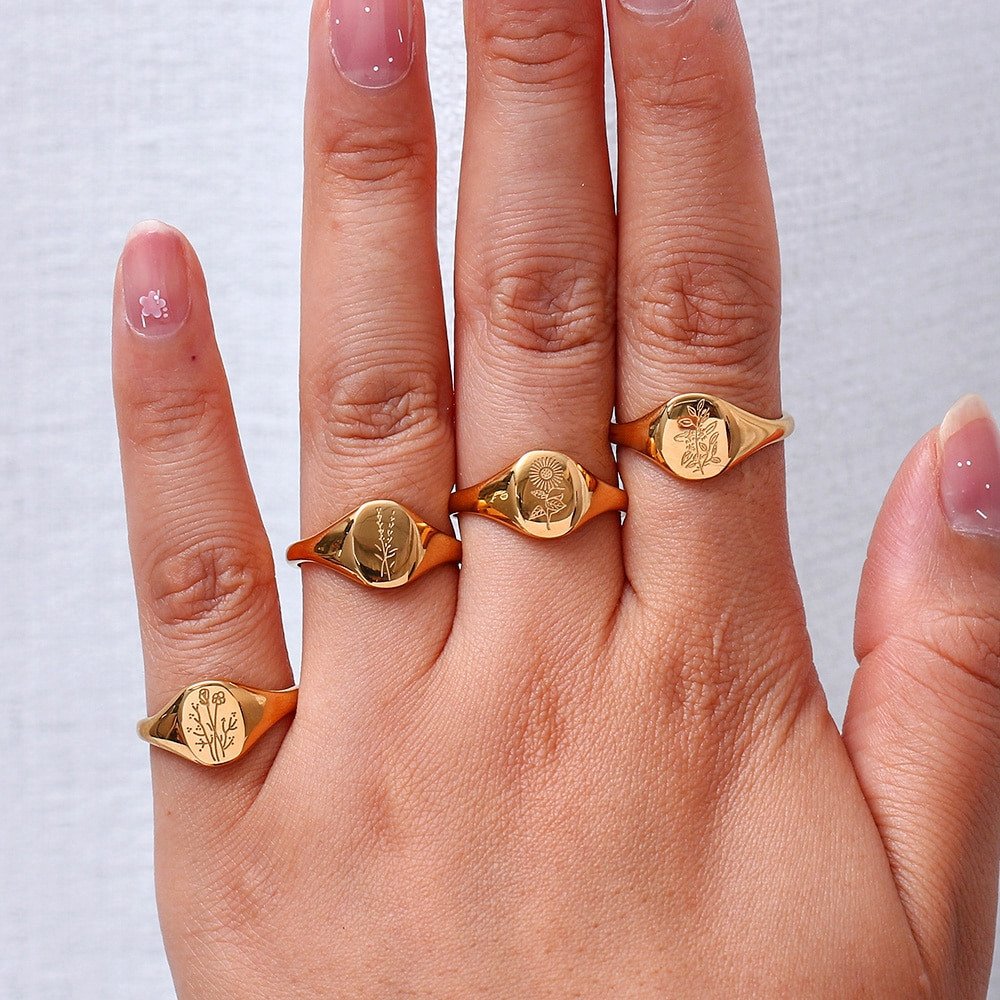 A model wearing four gold signet rings with floral designs.