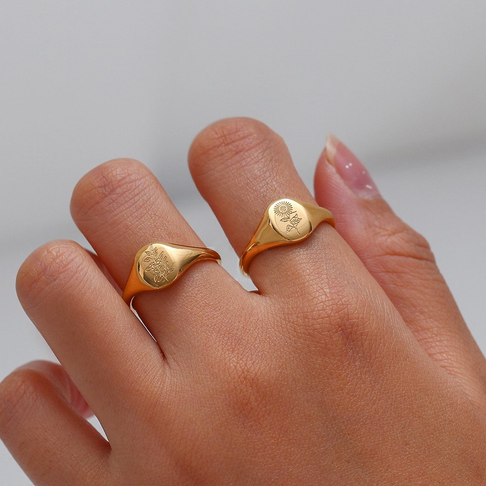 A model wearing two gold floral signet rings.