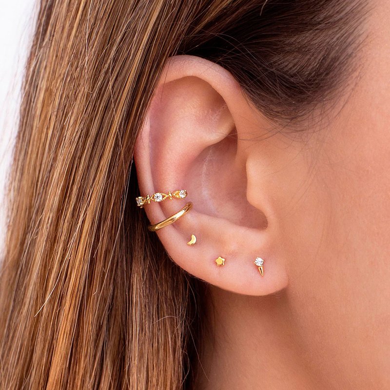 A model wearing tiny gold star and moon studs.