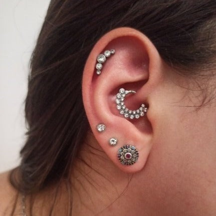 A woman wearing multiple silver CZ cartilage piercings.