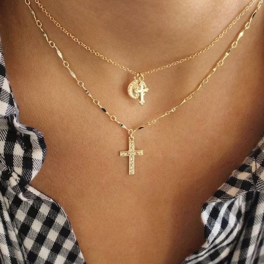 A model wearing a gold cross necklace.