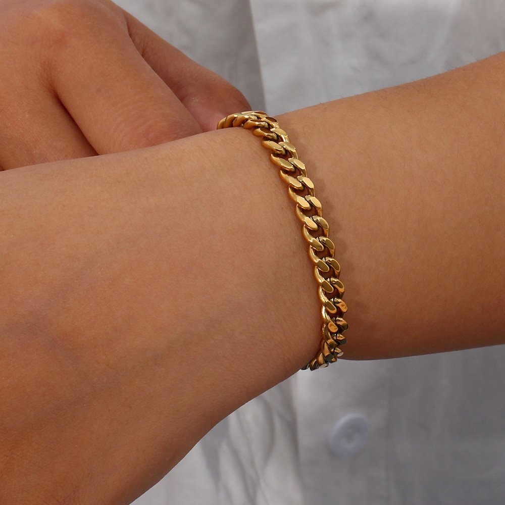 A woman wearing a gold cuban link bracelet.