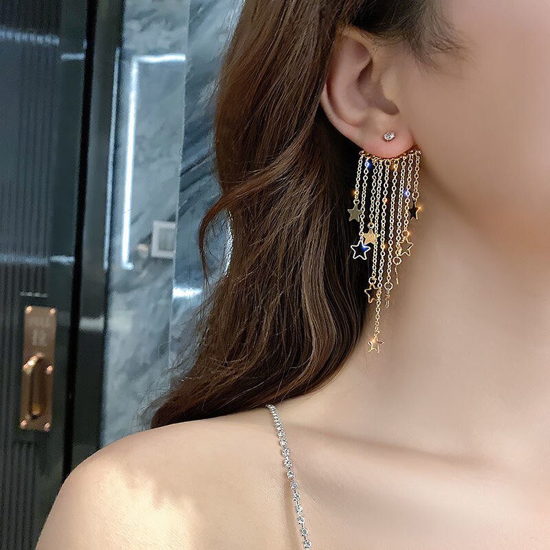 A model wearing Gold Star Tassel Statement Earrings.