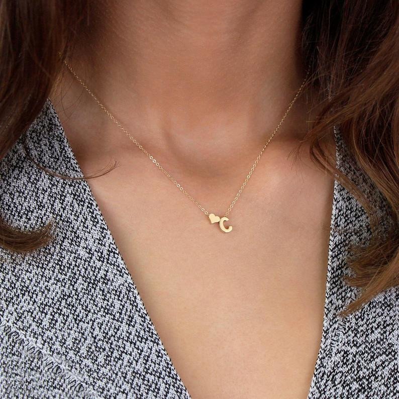 A model wearing a letter C initial necklace with heart charm.