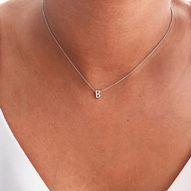 A model wearing a dainty necklace with an initial charm.