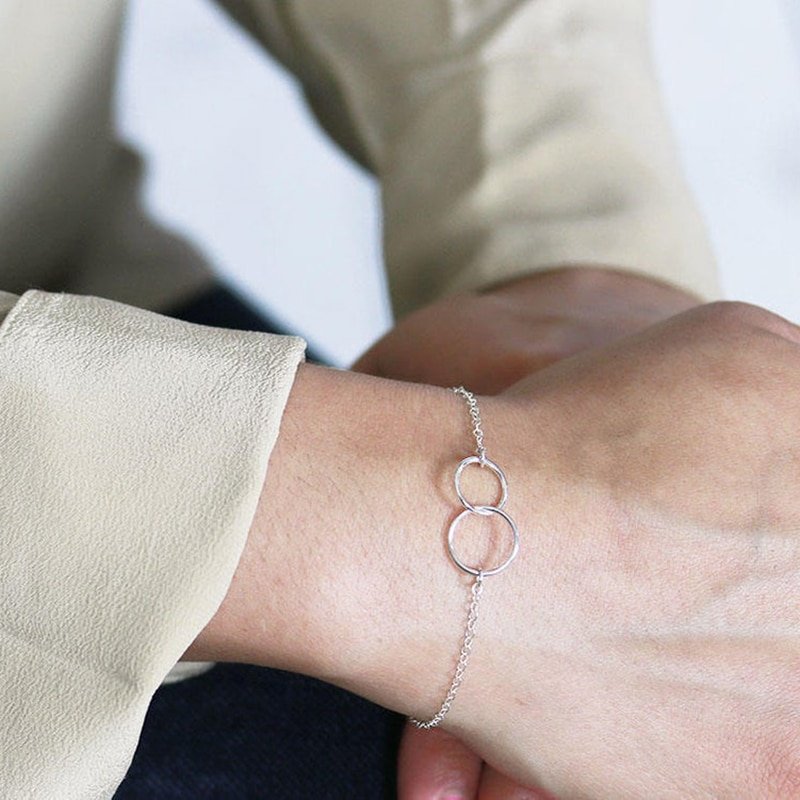 A model wearing a silver bracelet with two interlocking circles.