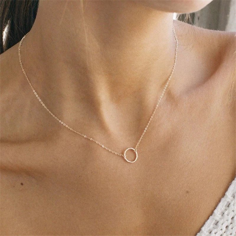 A model wearing a delicate gold necklace with circle pendant.